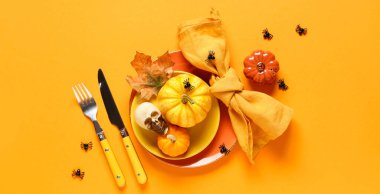 Turuncu arka planda Cadılar Bayramı kutlamaları için taze balkabakları, kafatası ve örümceklerle güzel bir masa.