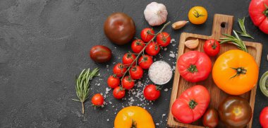 Siyah zemin üzerinde farklı taze domatesler olan tahta.