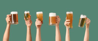 Yeşil arka planda bardaklar ve kupalar dolusu soğuk bira olan bir sürü el. Ekim Festivali Kutlaması