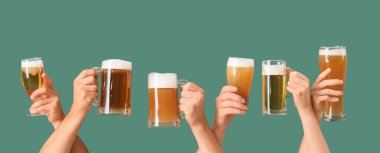 Yeşil arka planda bardaklar ve kupalar dolusu soğuk bira olan bir sürü el. Ekim Festivali Kutlaması