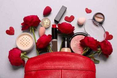 Makyaj ürünleri ve beyaz arka planda kırmızı güller olan kozmetik çanta. Sevgililer Günü kutlaması