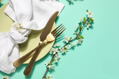 Turkuaz arka planda çiçek açan bir dalı olan güzel masa ayarları