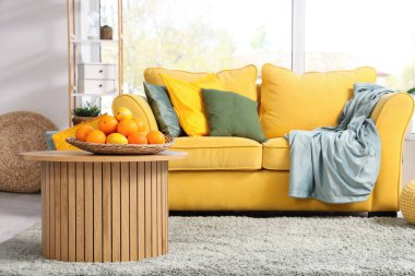 Açık oturma odasındaki sehpanın üzerinde narenciye tabağı var.