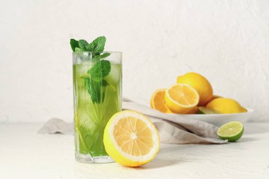 Bir bardak limonlu lezzetli limonata ve beyaz arka planda nane şekeri.