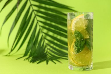Limon dilimli bir bardak lezzetli limonata ve yeşil arkaplanda nane.