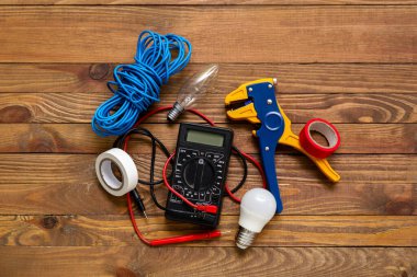 Elektrikçi aletleri, ampuller ve ahşap arka planda kablo seti