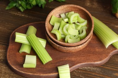 Ahşap zemin üzerinde taze yeşil kereviz kesilmiş yemek ve kase.