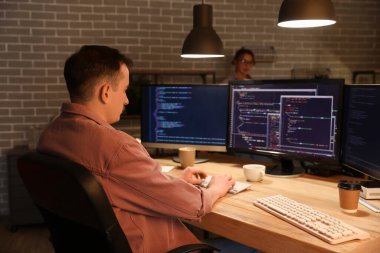 Erkek programcı geceleri ofiste bilgisayarla çalışıyor.