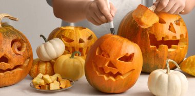 Bıçaklı kadın beyaz arka planda Cadılar Bayramı için farklı balkabakları oyuyor.