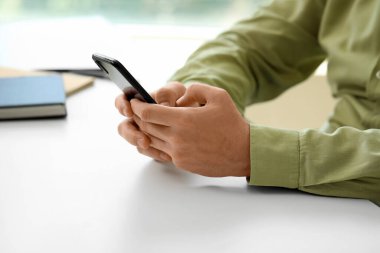 Sofrada akıllı telefonu olan adam, yakın plan.