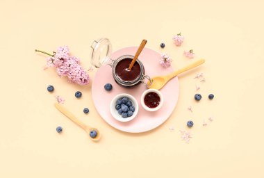 İçinde tatlı reçel kavanozu ve bej arka planda taze yaban mersini olan tahta.