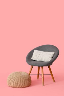 Pembe arka planda yastıklı gri koltuk