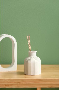 Renkli duvarın yanındaki masada bir şişe sazlık ayırıcı var.