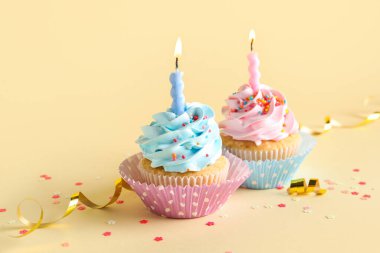 Sarı arka planda yanan mumları olan enfes doğum günü kekleri.