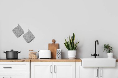 Modern mutfağın içinde mutfak aletleri, lavabo ve elektrikli soba beyaz tezgahlarda.