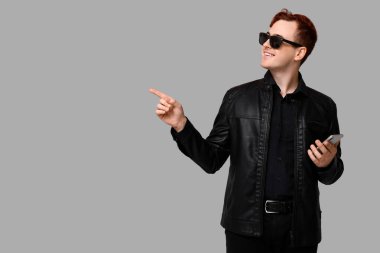 Cep telefonu olan genç adam gri arka plandaki bir şeyi işaret ediyor. Kara Cuma indirimi