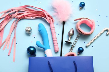 Seks oyuncakları ve mavi arka planda Noel dekoru olan bir alışveriş çantası.