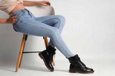 Beyaz arka planda sandalyede oturan şık pantolonlu genç kadın.