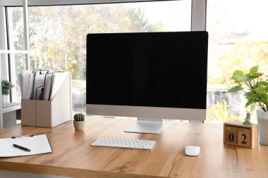 Ofisteki pencerenin yanında dizinleri ve bitkileri olan boş bilgisayar monitörü