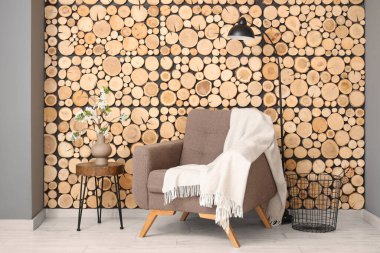 Oturma odasındaki koltuğun yanındaki sehpanın üzerinde çiçek açan bir vazo.