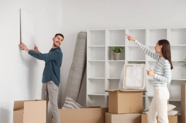 Genç bir çift taşınma gününde duvarlara resim asıyor.