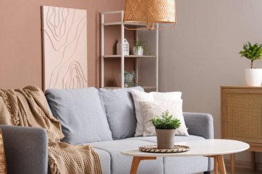 Gri kanepesi ve bej duvarın yanında kahve masası olan şık bir oturma odası.