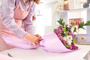 Kadın çiçekçi el sanatları kağıdına sarılıyor Çiçekçide güzel bir demet leylak