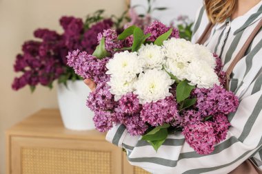 Çiçekçide elinde leylaklarla güzel bir buket tutan kadın çiçekçi.