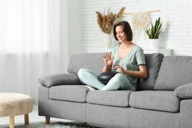 Genç bir kadın evde glukofon çalıyor.