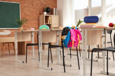 Sıraları ve sırt çantaları olan sınıfın içi