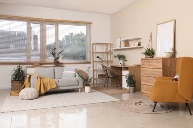 Kahverengi koltuklu şık bir oturma odası, çekmeceler, iş yeri ve rahat bir kanepe.