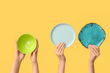 Sarı arkaplanda boş tabakları tutan eller