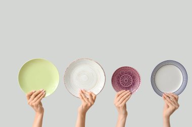 Açık arkaplanda boş tabakları tutan eller