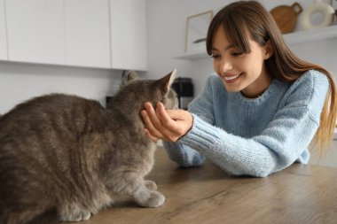 Güzel, genç, mutlu bir kadın ve evde sevimli bir kedisi var.