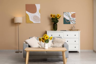 Kanepe, masa ve vazolarla oturma odasının içinde güzel ayçiçekleri var.