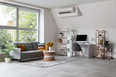 Oturma odasının içinde gri kanepe, modern çalışma alanı ve kahve masasında ayçiçekleri.