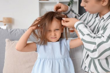 Anne evde küçük kızının kafasını pedikülozla kontrol ediyor.