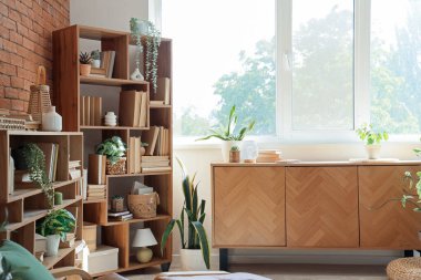 Ev kütüphanesinin iç kısımlarında kitap ve bitkilerle dolu çekmece ve kitaplık.