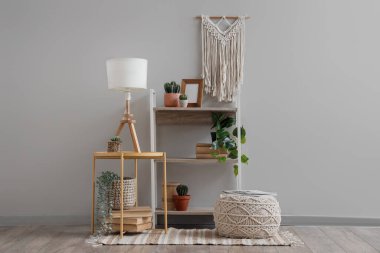 Rafa kaldırma ünitesi, içinde lamba ve pouf olan kahve masası oturma odasının içinde.