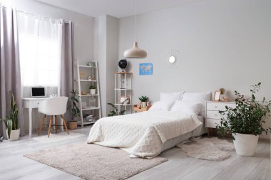 Yatağı, raf üniteleri ve çalışma masası olan hafif ergen odasının içinde.