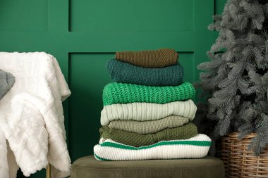 Pouf 'un üstündeki kışlık giysiler ve yeşil duvarın yanındaki Noel ağacı, yakın plan.