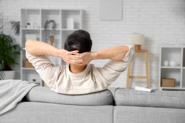 Yakışıklı genç adam oturma odasında klimayla rahatlıyor.