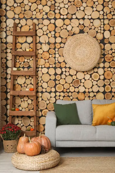 Gri kanepe, hasır puf ve balkabağı olan rahat bir oturma odası.