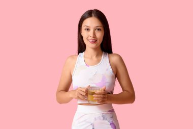 Güzel, genç, mutlu bir Asyalı kadın. Pembe arka planda kilo kaybı için bir fincan çay.