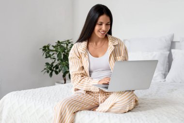 Güzel bir kadının yatak odasında dizüstü bilgisayar kullandığı bir sabah.