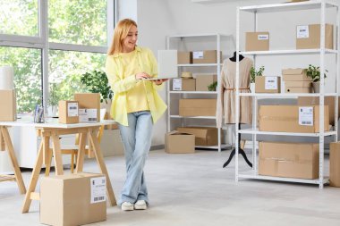 İnternetteki depo deposunda dizüstü bilgisayarla çalışan kadın satıcı.