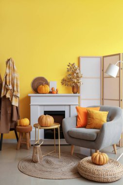 Oturma odasının içinde koltuk, şömine ve sonbahar dekoru var.