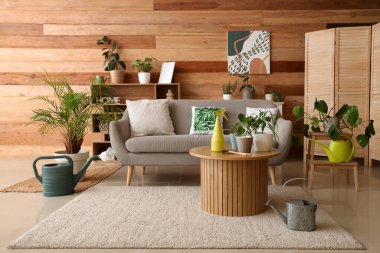 Oturma odasının içinde kanepe, yeşil bitkiler ve bahçe aletleri var.