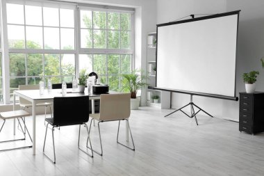 Projektör ekranı ve toplantı tablosu olan ofis içi