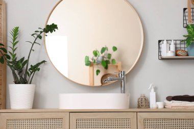 Modern lavabo, çekmeceler ve banyo duvarının yanındaki bitkiler.